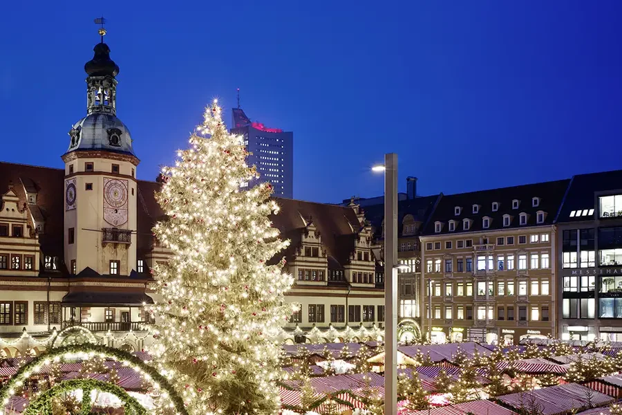 Leipziger Weihnachtsmarkt auf dem Marktplatz bei Nacht mit beleuchtetem Weihnachtsbaum und historischer Kulisse des Alten Rathauses.